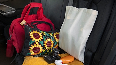 Rote Tasche, Tasche mit Sonnenblumenmuster und ein Fotoapparat liegen im Bus und wurden vergessen.